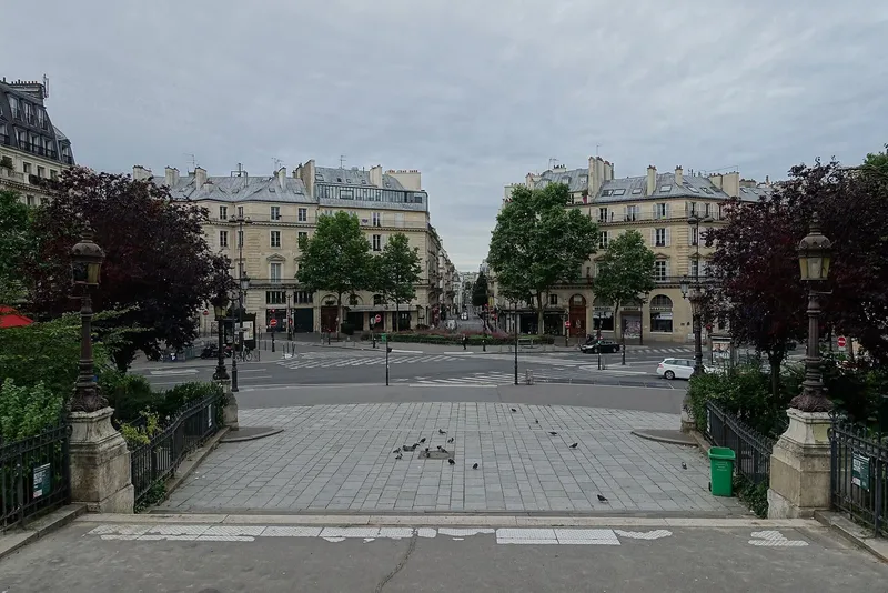 Photographie : une place pavée bordée d'immeubles de pierre et d'arbres