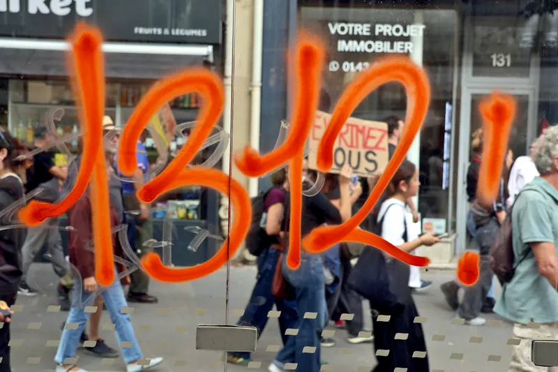« 1312 ! » peint en orange sur une vitrine, derrière laquelle passe le cortège