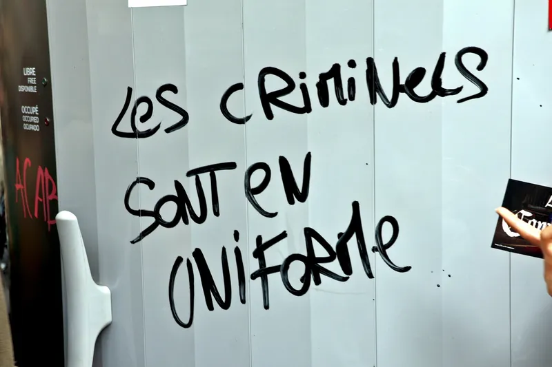 Graffiti au feutre noir sur une sanisette : « Les criminels sont en uniforme »
