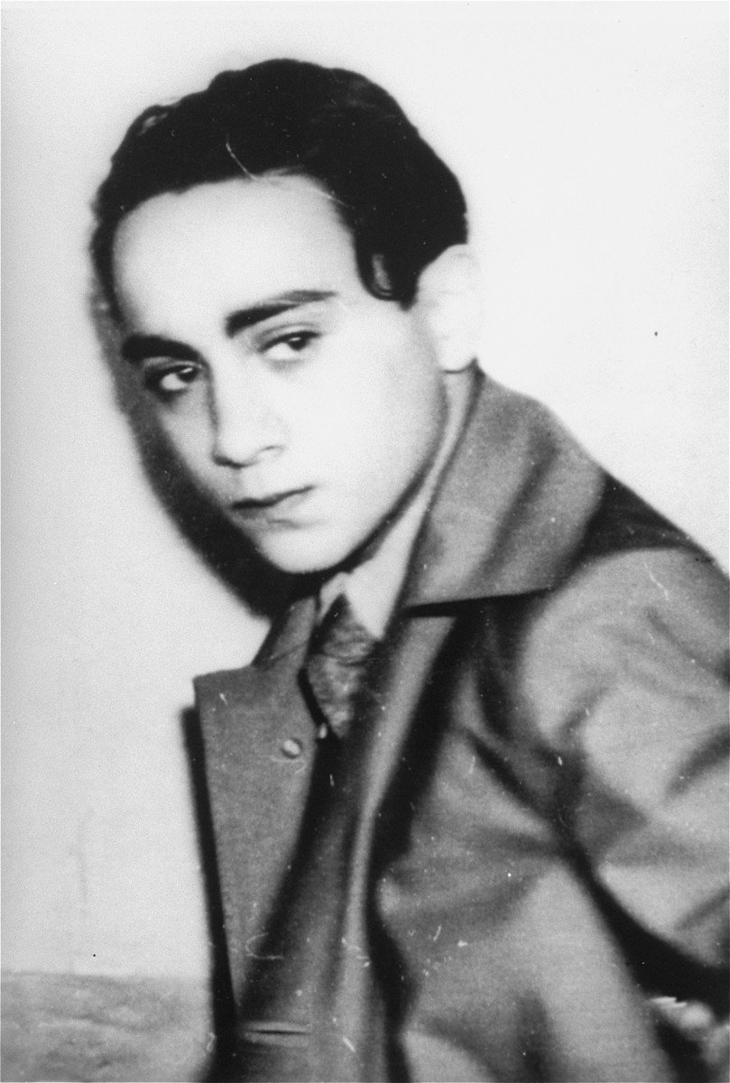 Herschel Grynszpan après son arrestation, en novembre 1938 — Bundesarchiv, Bild 146-1988-078-07 · CC BY-SA 3.0 de — Wikimedia Commons Photographie en noir et blanc : portrait d’Herschel Grynszpan, jeune homme aux cheveux noirs, en manteau, le regard fixe