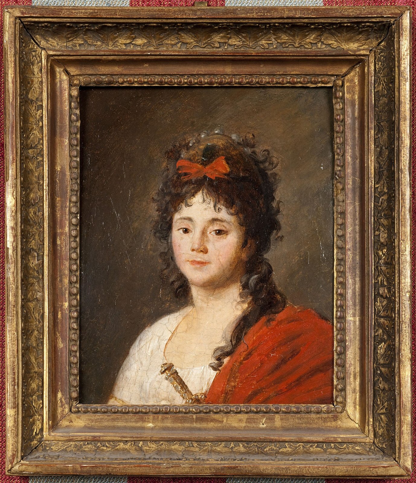 Mlle Maillard (Marie-Thérèse Davoux, 1766-1818), chanteuse de l’Opéra, portrait attribué à Jean-François Garnerey, vers 1790 (musée Carnavalet) — Paris Musées · CC0 — Wikimedia Commons Portrait peint dans un cadre doré : une jeune femme aux cheveux bruns bouclés noués d’un ruban rouge, en chemise blanche et châle rouge
