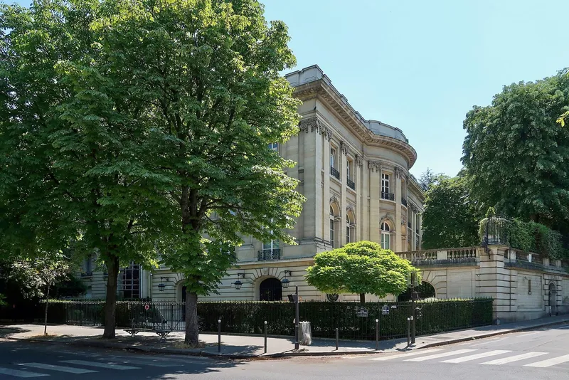Photographie : un hôtel particulier de pierre derrière un rideau d'arbres