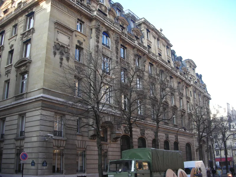 Photographie : la façade de pierre de l’ancien hôtel Majestic, avenue Kléber, derrière une rangée d’arbres sans feuilles