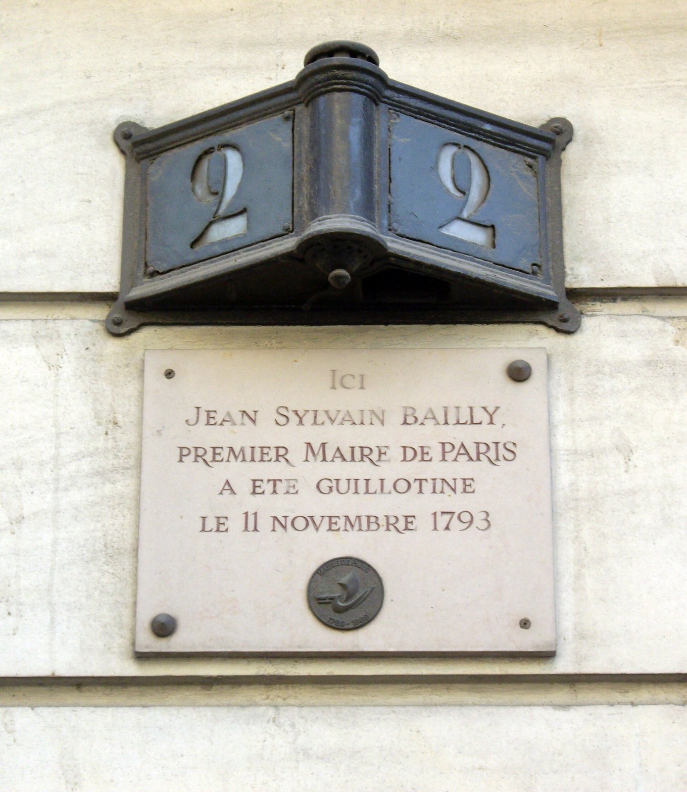 La plaque du 2 avenue de La Bourdonnais, au bord du Champ-de-Mars — Mu · CC BY-SA 3.0 — Wikimedia Commons Photographie : sous un numéro 2 en émail bleu, une plaque de pierre : « Ici Jean Sylvain Bailly, premier maire de Paris, a été guillotiné le 11 novembre 1793 »