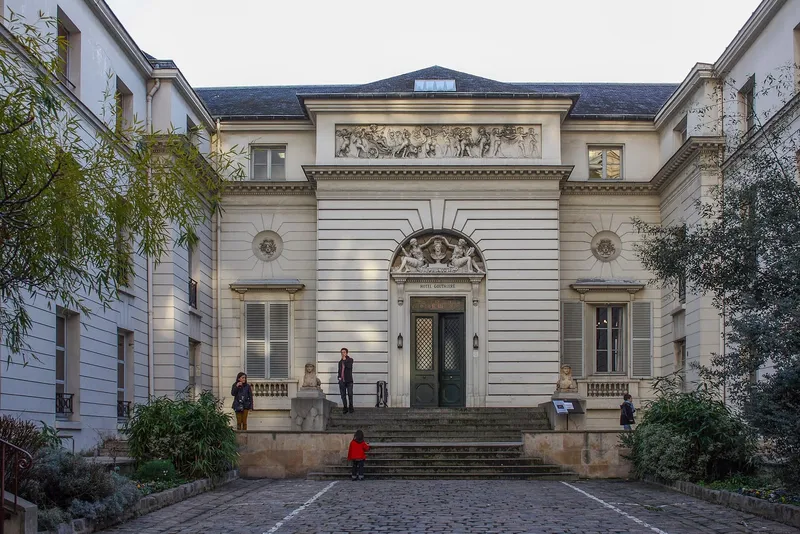 Photographie : un hôtel néoclassique au fond d'une cour, avec un perron et un portail cintré