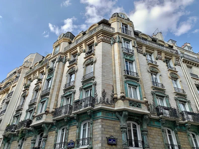 Photographie : un immeuble d'angle Art nouveau, sa façade couverte de céramique ocre et verte