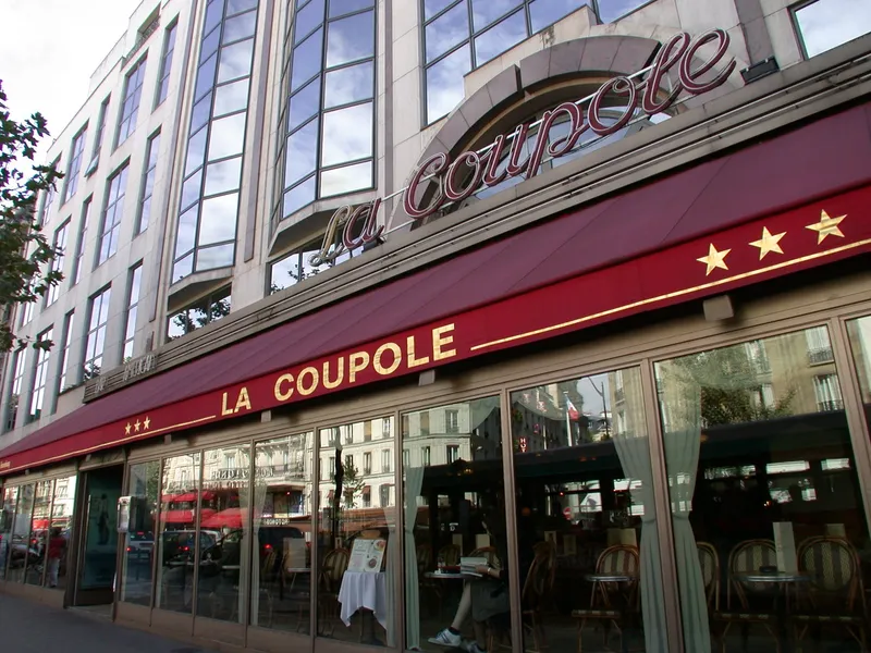 Photographie : la façade de La Coupole, boulevard du Montparnasse, avec son enseigne lumineuse et sa marquise rouge