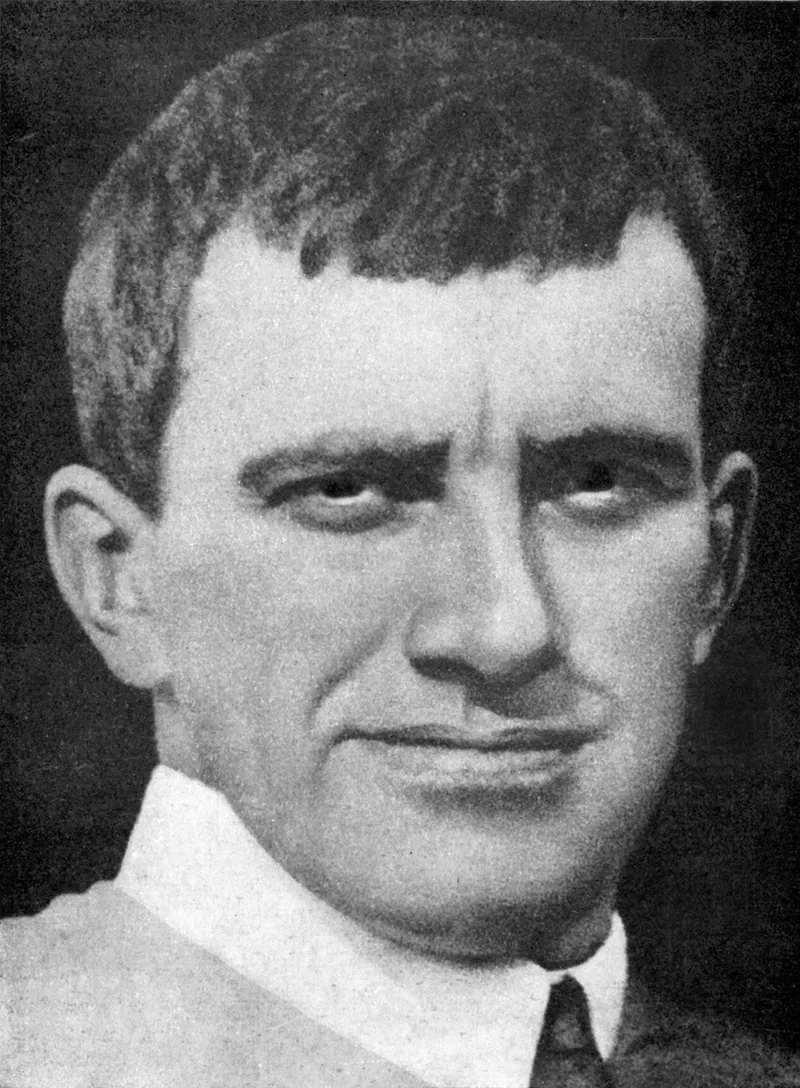 Photographie en noir et blanc : portrait en buste de Vladimir Maïakovski, cheveux courts, regard sombre, en chemise à col ouvert