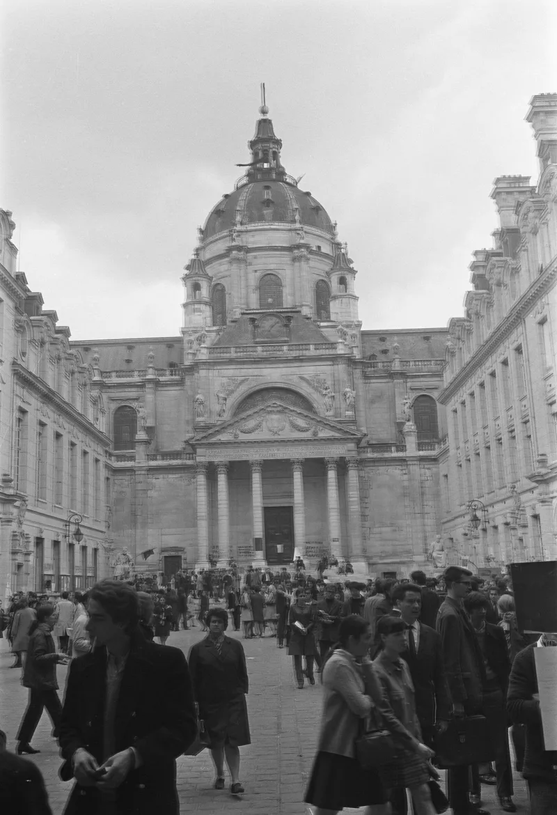 Photographie en noir et blanc : des étudiants dans la cour de la Sorbonne, devant la façade et le dôme de la chapelle
