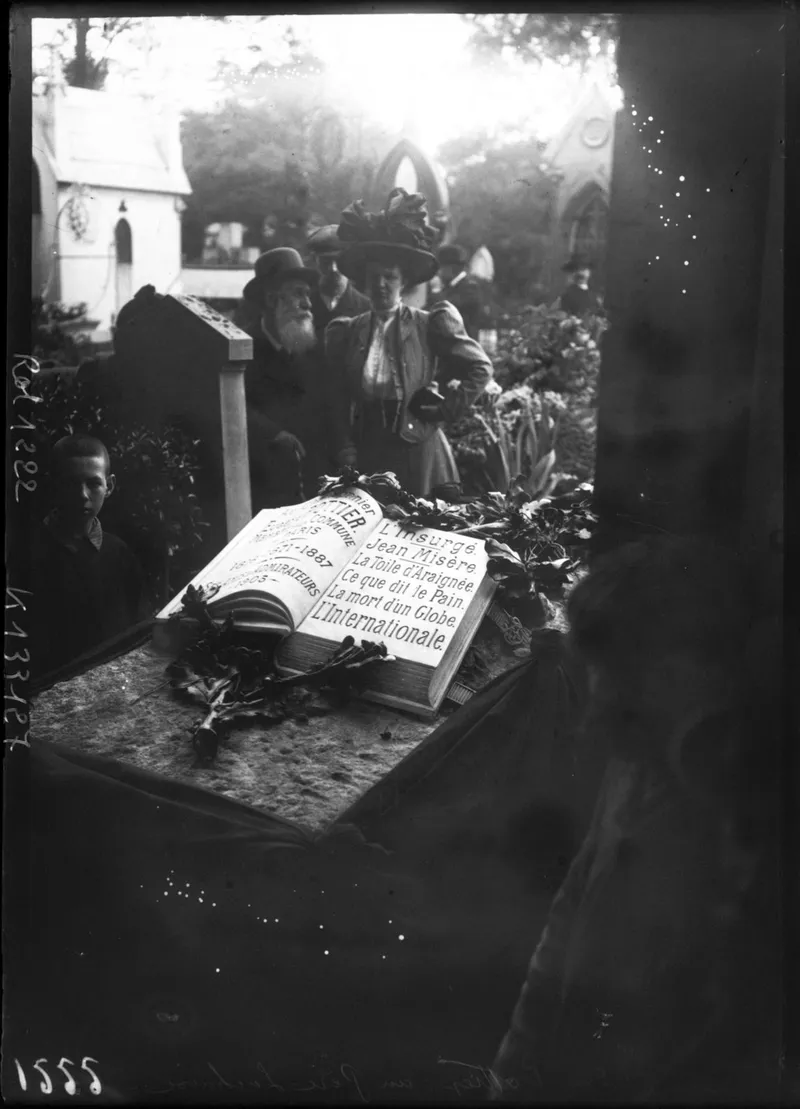 Photographie ancienne : la tombe de Pottier, un livre de marbre ouvert gravé des titres de ses chansons, couverte de couronnes, devant quelques visiteurs