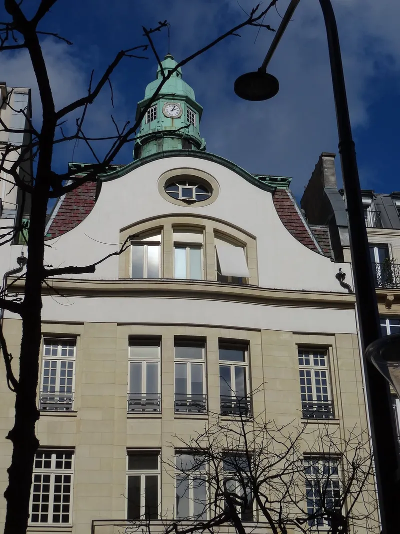 Photographie : une façade blanche à fronton courbe, coiffée d'un campanile vert en forme de phare