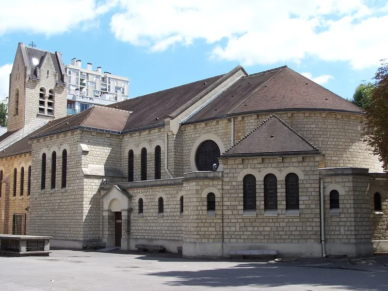 Photographie : une église de pierre à clocher, au fond d'une esplanade