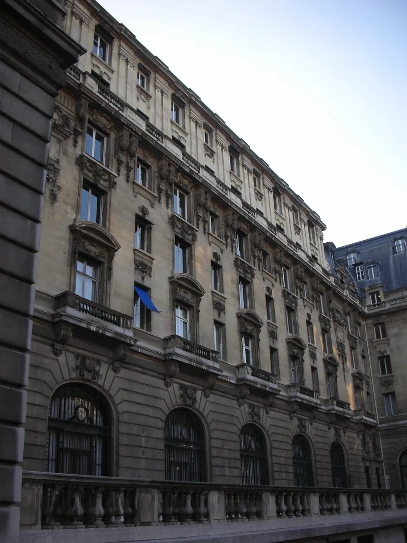 Photographie : vue en contre-plongée de la façade de pierre de l'ancien hôtel Majestic, avec ses balcons de fer forgé, ses fenêtres sculptées et ses grandes baies cintrées au rez-de-chaussée