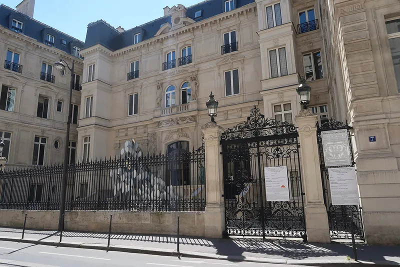 Photographie : la façade de pierre d'un hôtel particulier derrière une haute grille
