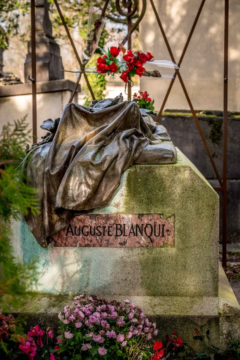 Photographie : le gisant de bronze d'Auguste Blanqui par Jules Dalou, fleuri