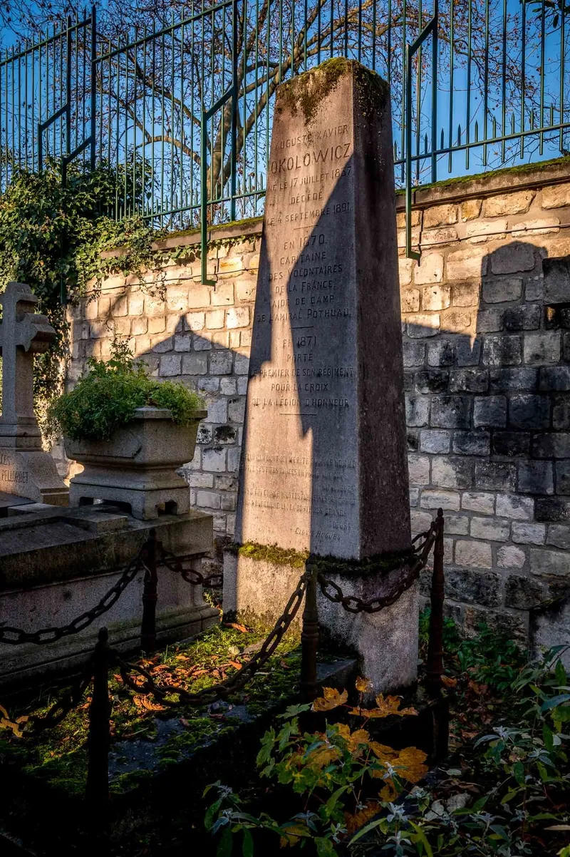 Photographie : la tombe d'Auguste Okolowicz au pied du mur d'enceinte du Père-Lachaise