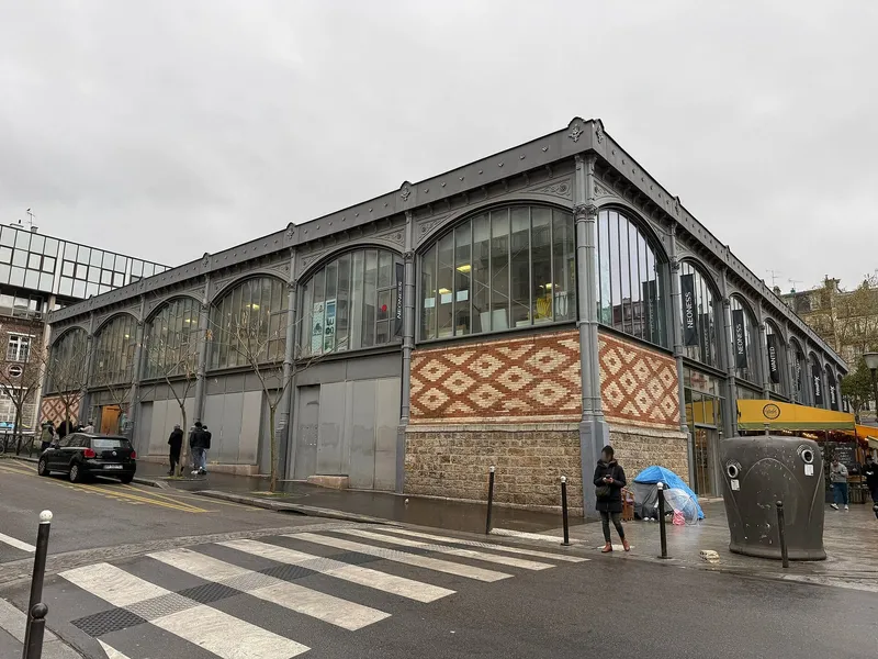 Photographie : une halle à charpente métallique et grandes verrières, sur un soubassement de brique